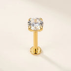 Gold titanium Ashley solitaire piercing worn in the center of the lower lip
