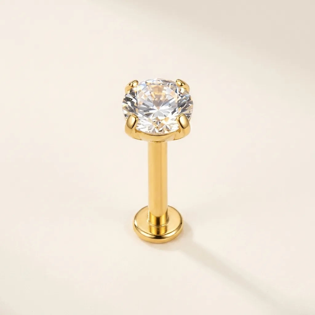 Gold titanium Ashley solitaire piercing worn in the center of the lower lip

