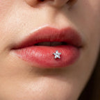 Silver titanium Ashley star cut piercing worn in the center of the lower lip
