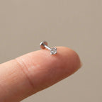 Flat back titanium Ashley solitaire labret shown on a fingertip for scale
