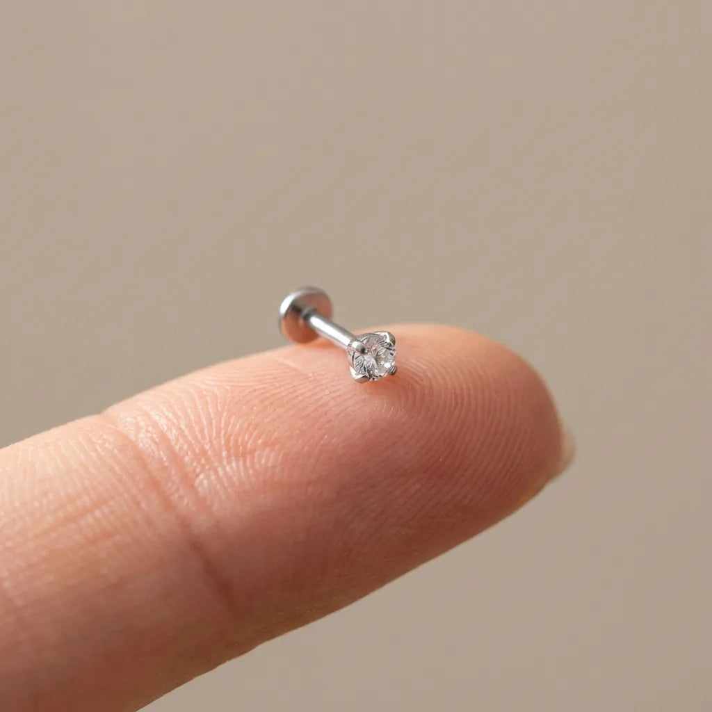 Flat back titanium Ashley solitaire labret shown on a fingertip for scale
