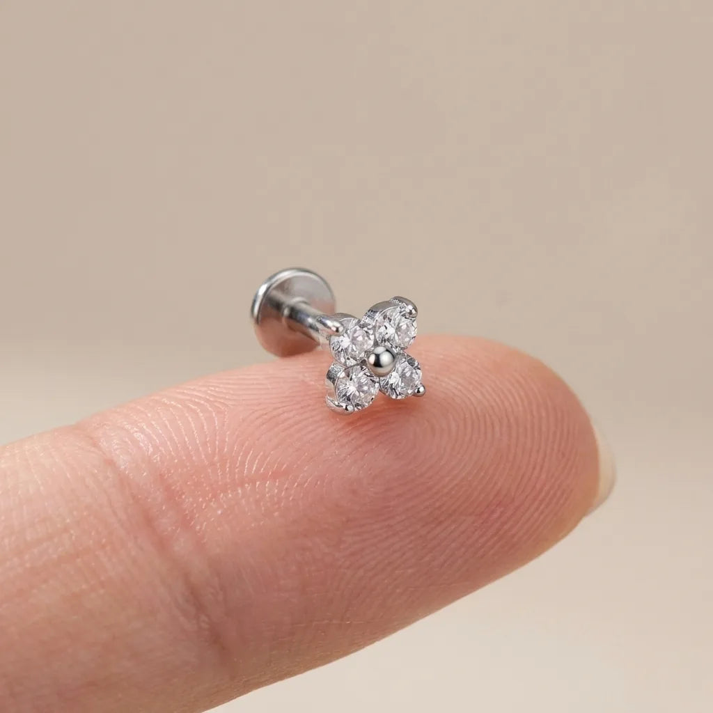Flat back titanium Ashley clover labret shown on a fingertip for scale
