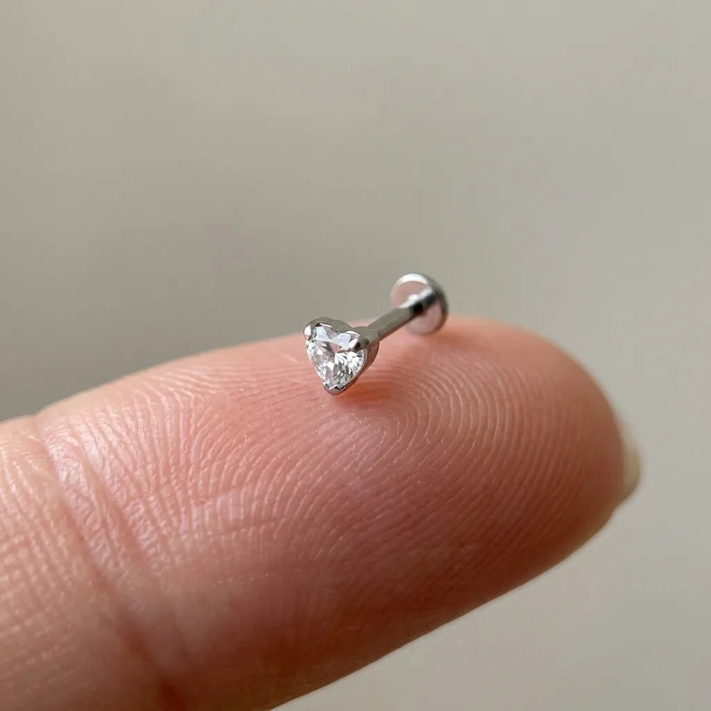 Flat back titanium Ashley heart labret shown on a fingertip for scale
