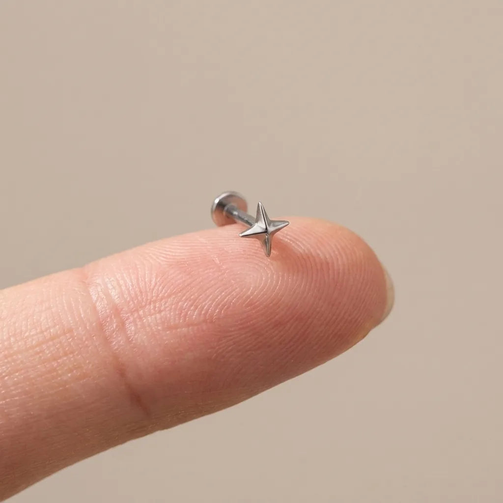 Flat back titanium Ashley star labret shown on a fingertip for scale

