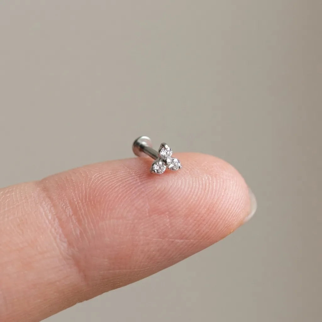 Flat back titanium Ashley trinity labret shown on a fingertip for scale
